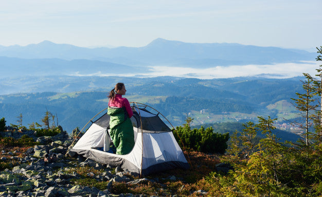 Frau genießt Ausblick vom Berg aus dem Zelt am Morgen